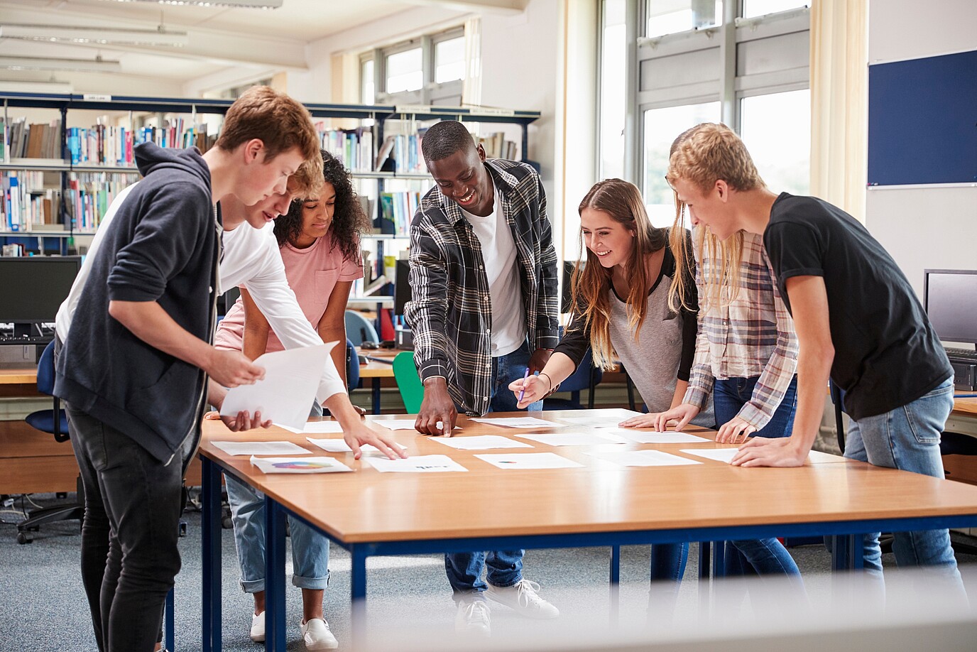 Sozialarbeiter und Schüler stehen um einen Tisch und unterhalten sich.