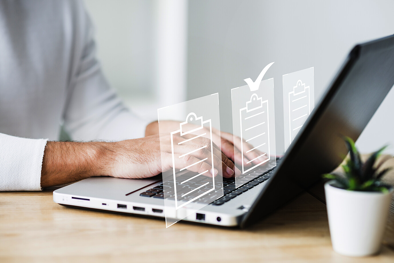 Eine Person arbeitet am Laptop. Über dem Laptop schweben Grafiken von Checklisten.