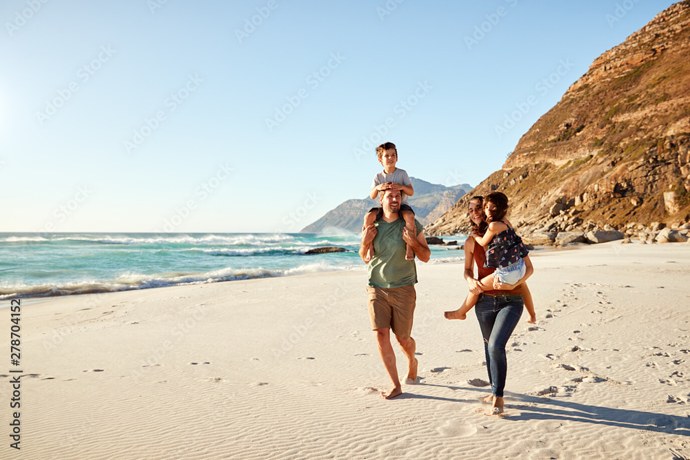 eine glückliche familie mit 2 kindern die am strand spazieren geht