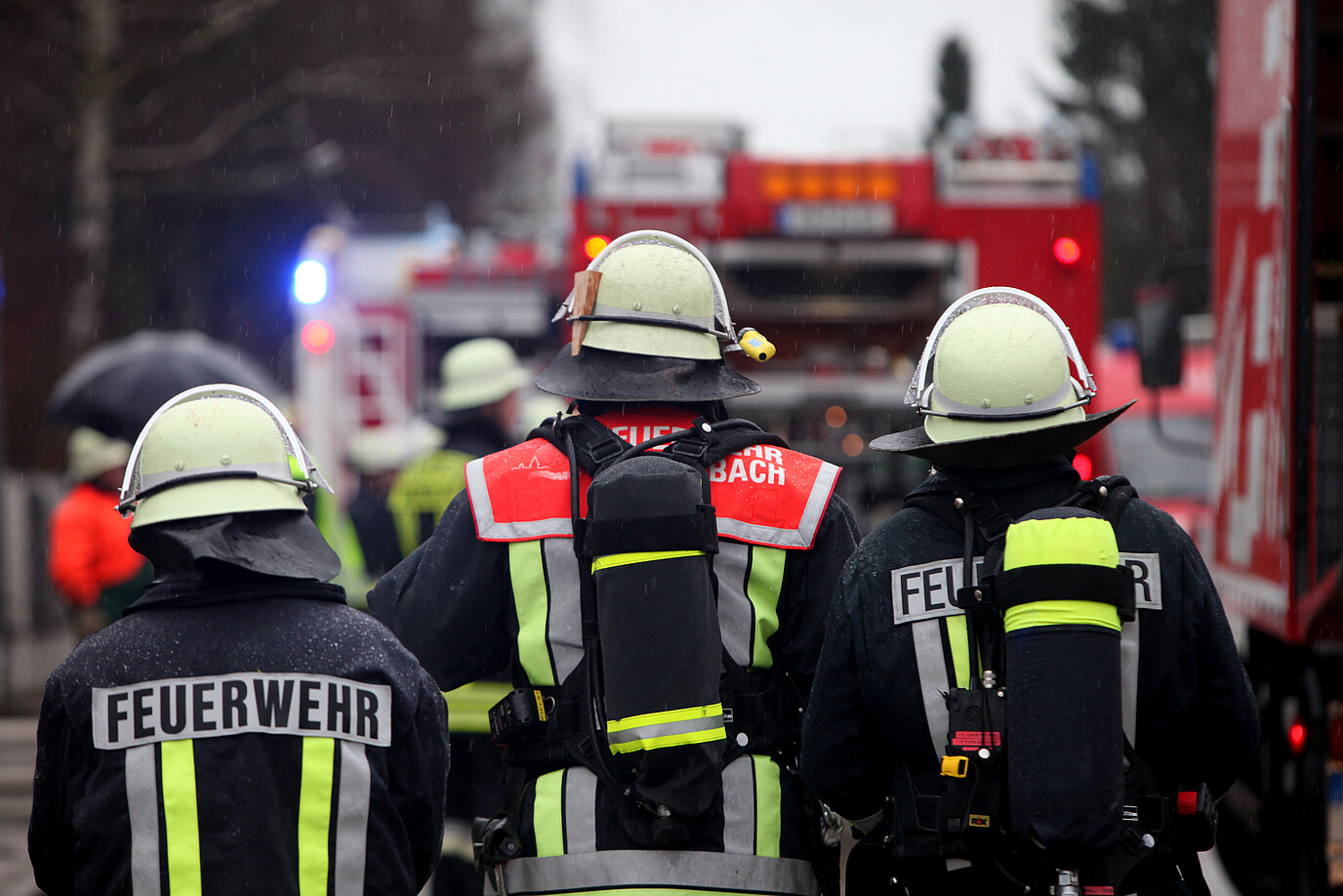 Drei Feuerwehrleute am Einsatzort, von hinten fotografiert.