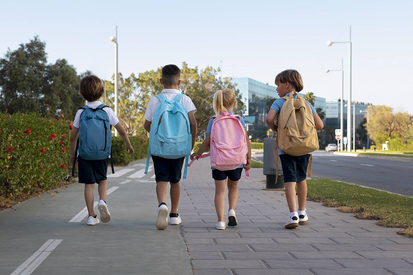4 Kinder mit Rucksäcken auf dem Schulweg.
