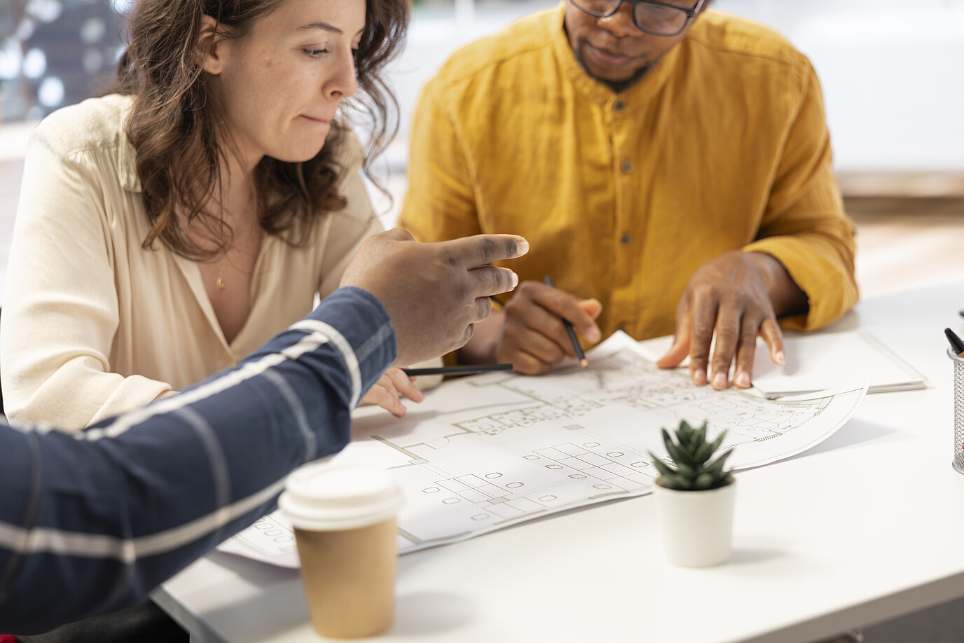 Kollegen besprechen sich an einem Tisch und schauen auf verschiedene Dokumente.